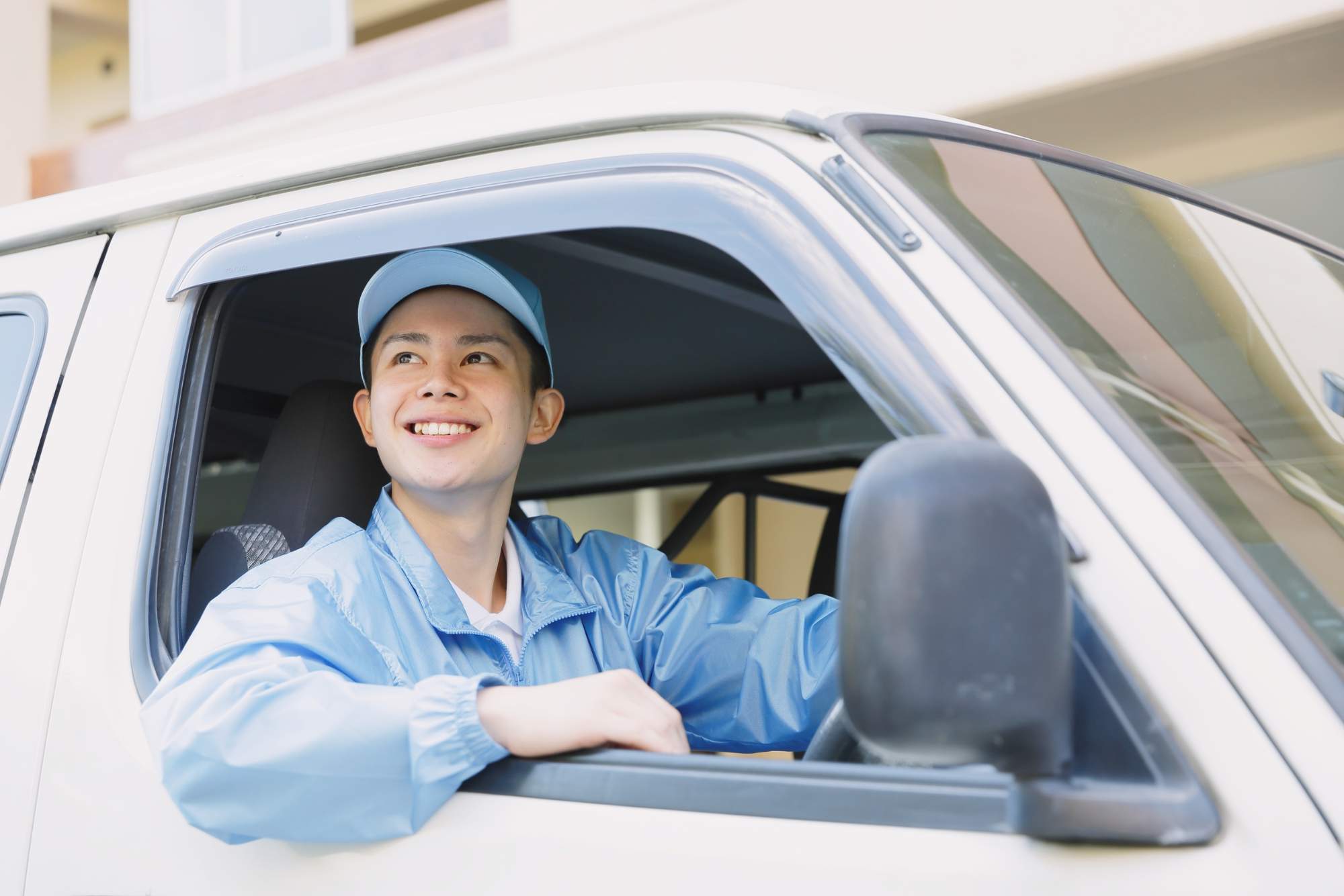 Amazon delivery driver in blue uniform smiling from delivery van
