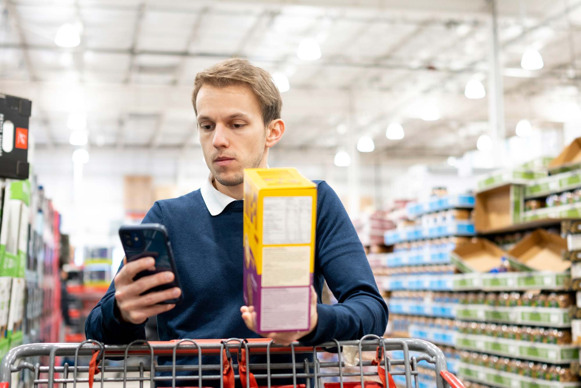 Instacart shopper checking phone while shopping in warehouse store